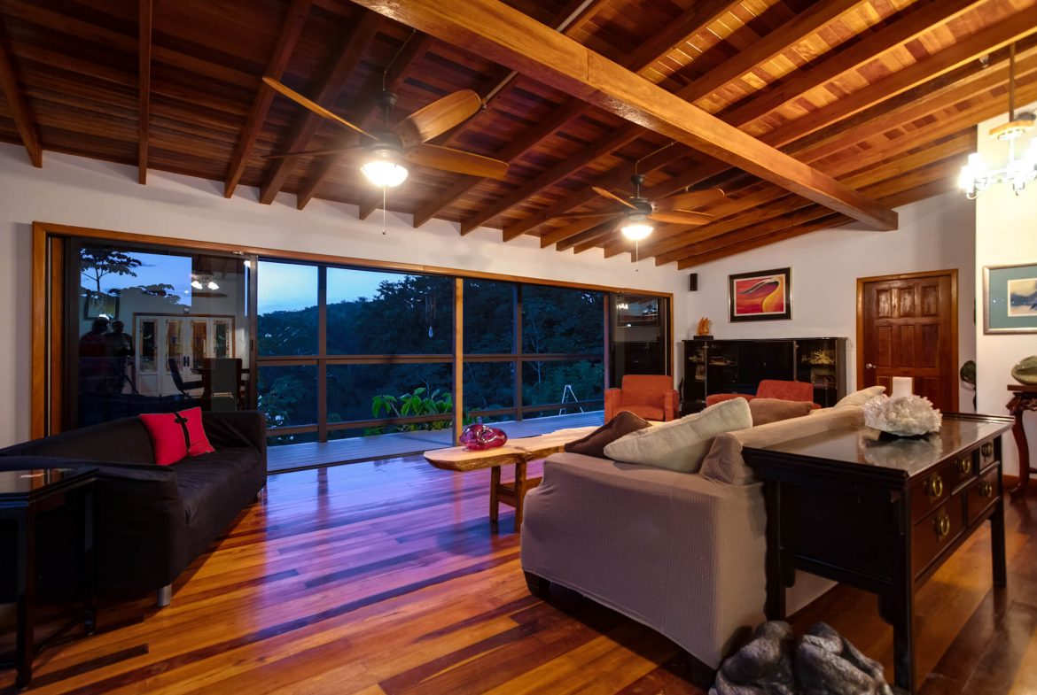 Photo of the living room in the main house on the 2.08-acre property in Cayo, Belize, showcasing beautiful wooden ceilings and comfortable furnishings.