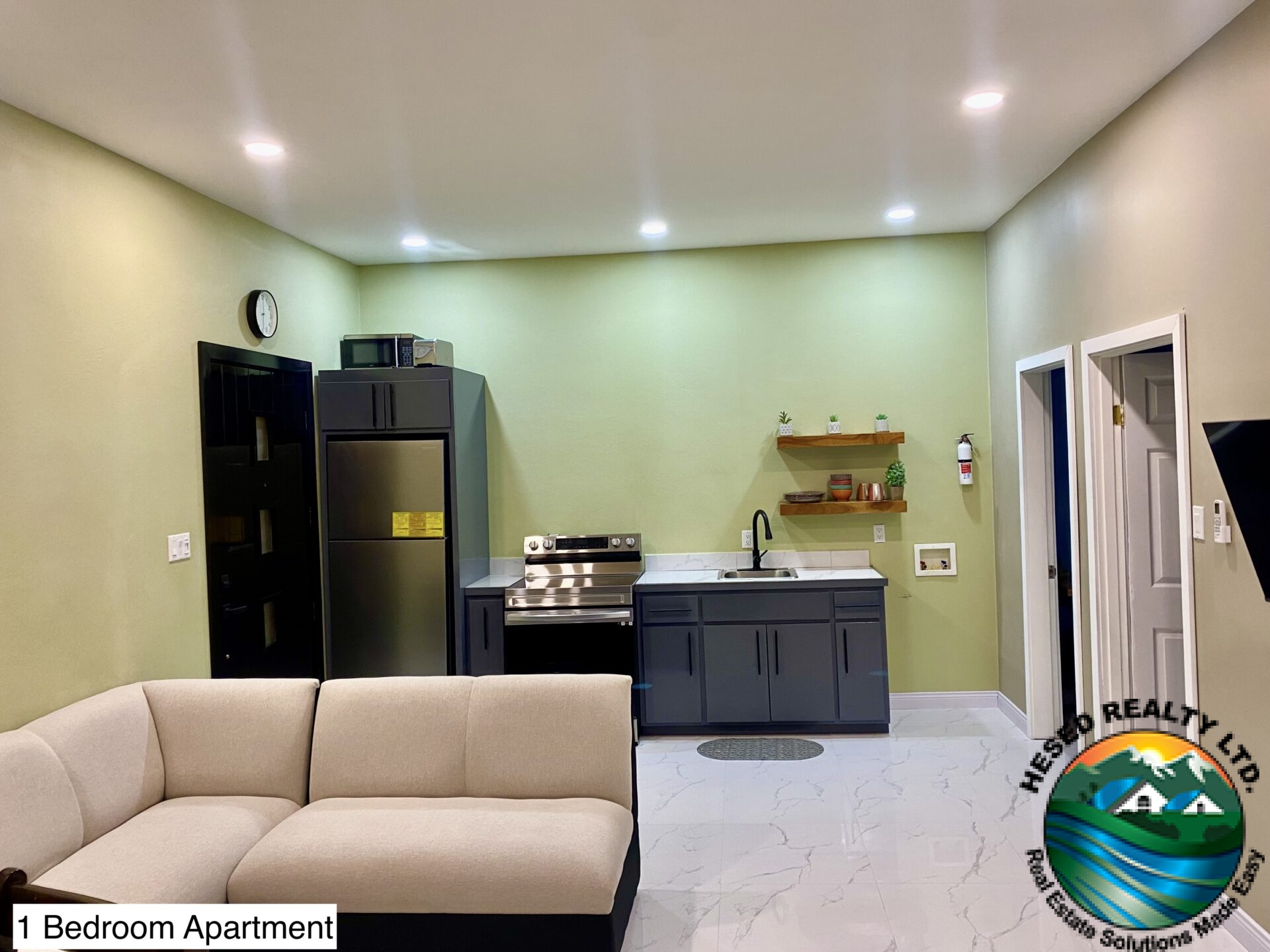 Modern kitchen in a 1-bedroom apartment with quartz countertops, flat-panel cabinets, and stainless steel appliances.