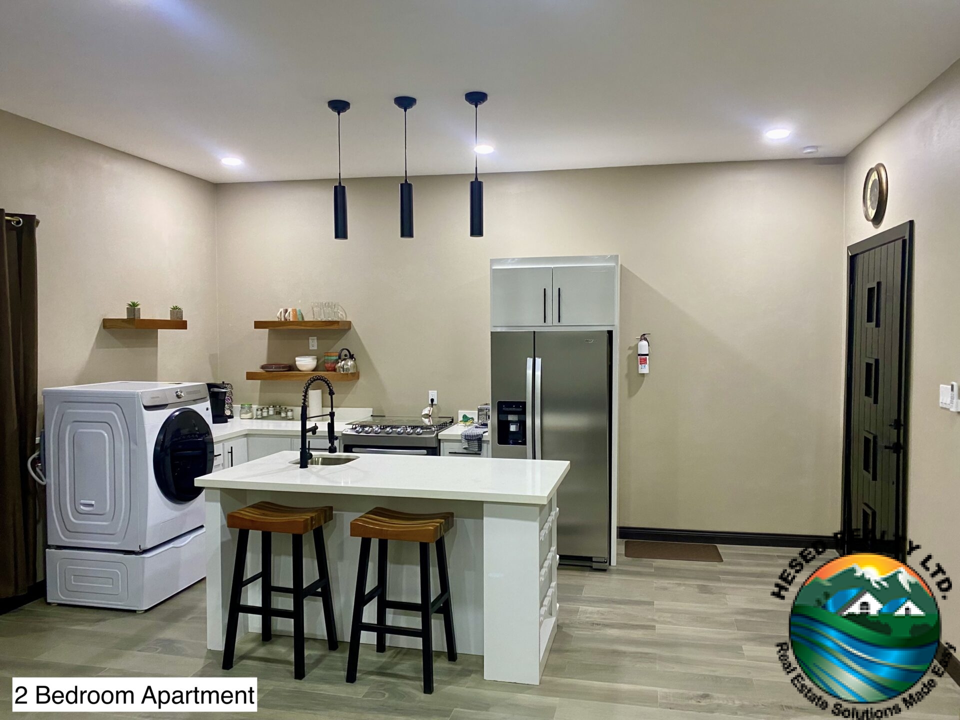 Modern kitchen in a 2-bedroom apartment with quartz countertops, flat-panel cabinetry, and stainless steel appliances.