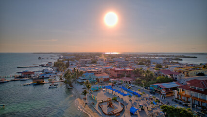 Aerial view of San Pedro Town, Ambergris Caye, Belize, showcasing colorful buildings lining the beachfront and turquoise waters of the Caribbean Sea.