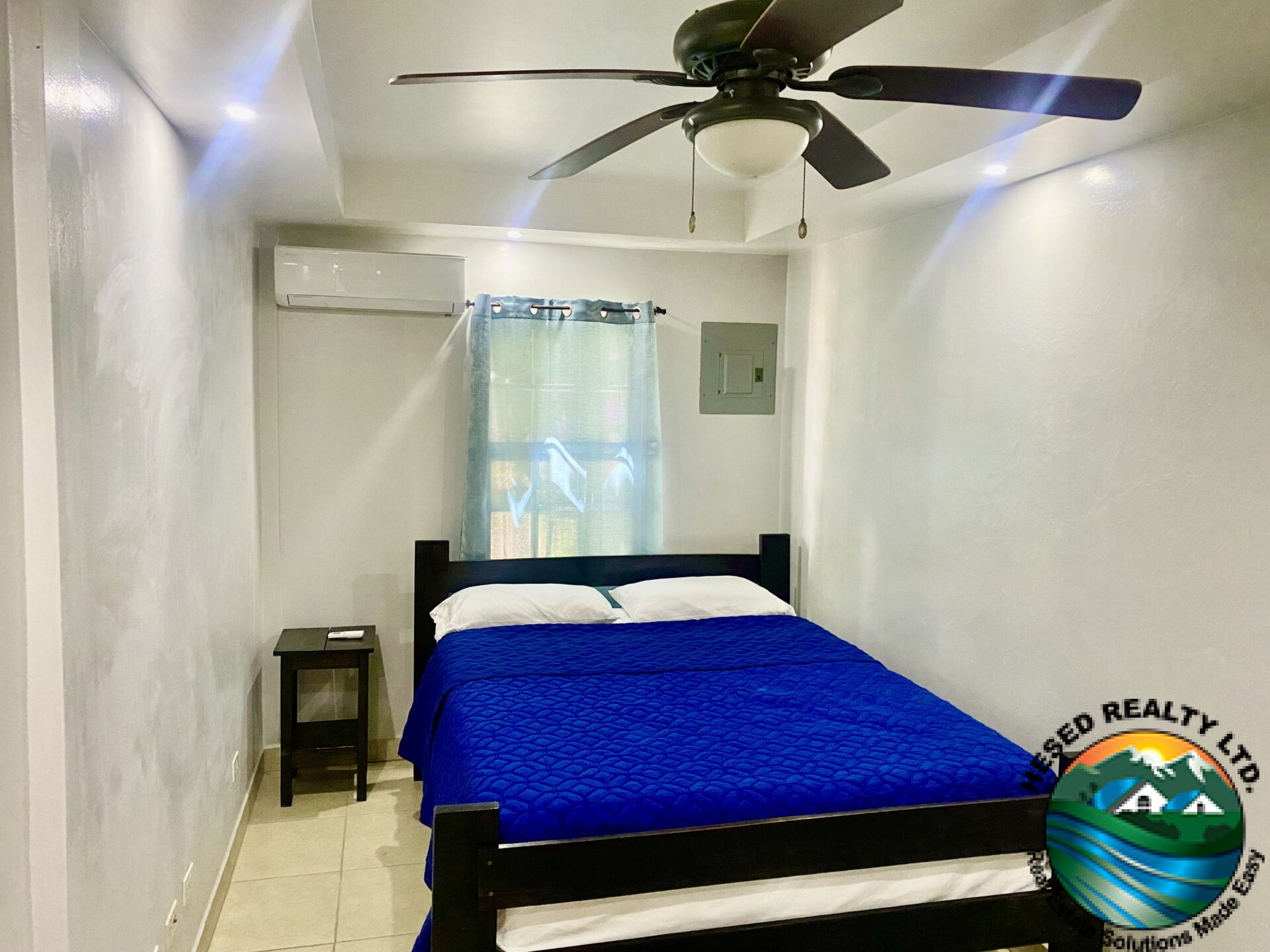 Bedroom of 1-bedroom apartment in Belmopan with air conditioning, natural light, and ample storage.