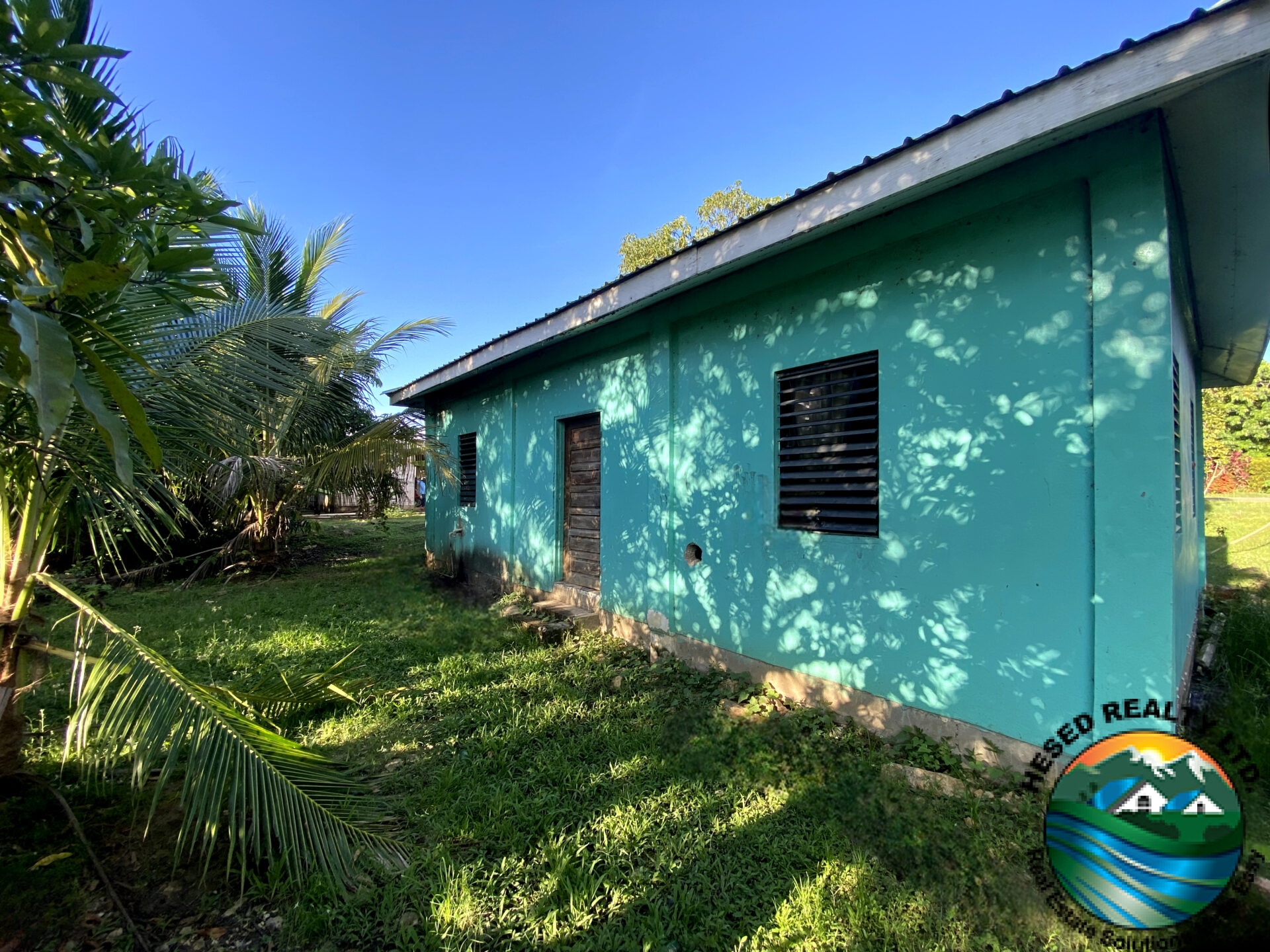 Back view of family home in Belmopan, Belize, featuring a large yard ideal for outdoor activities and family gatherings.