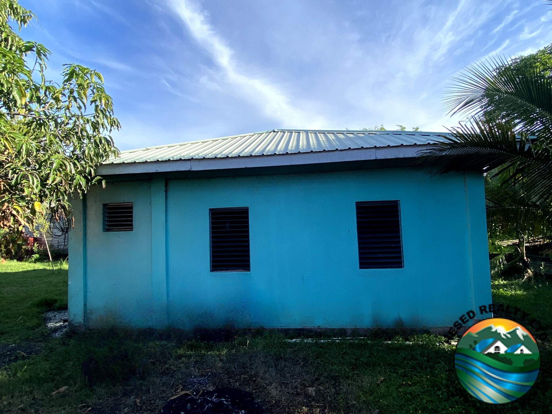 Side view of 2-bedroom family home in Belmopan, Belize, featuring extra yard space and secure structure.