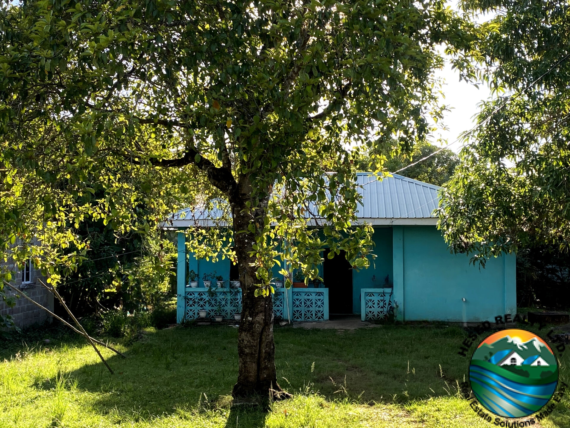 Front view of 2-bedroom family home in Belmopan, Belize, featuring a spacious yard and welcoming entrance.