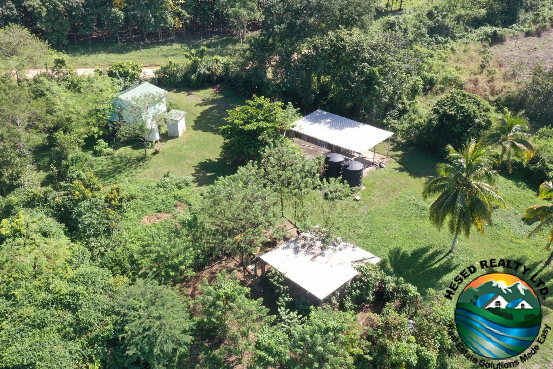 Drone shot of three buildings with a water reservoir visible on the property.