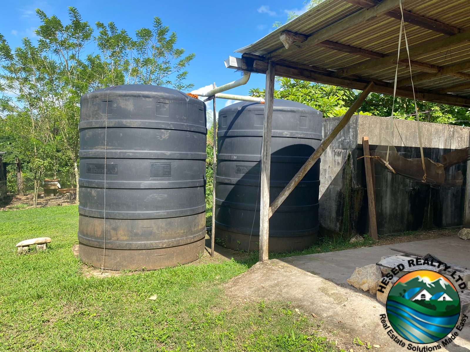 Two black plastic water tanks used for irrigation and water storage on the property.